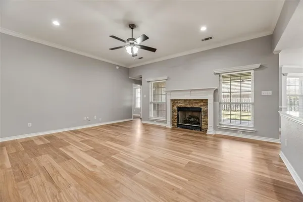 an empty room with windows fireplace and wooden floor