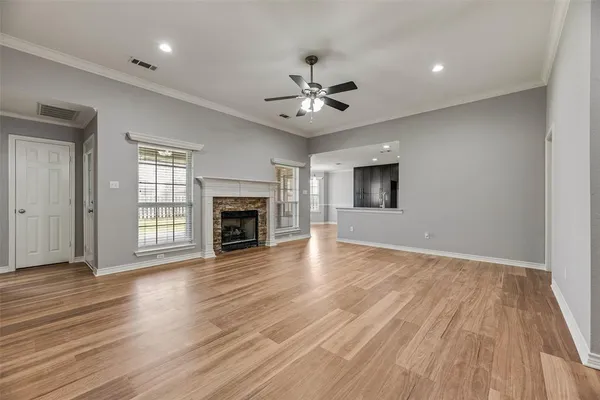 an empty room with wooden floor fireplace and windows