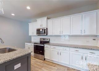 8550 River Ridge Drive Charlotte, NC 28213 - Photo 4 of 25 a kitchen with granite countertop white cabinets stainless steel appliances and sink