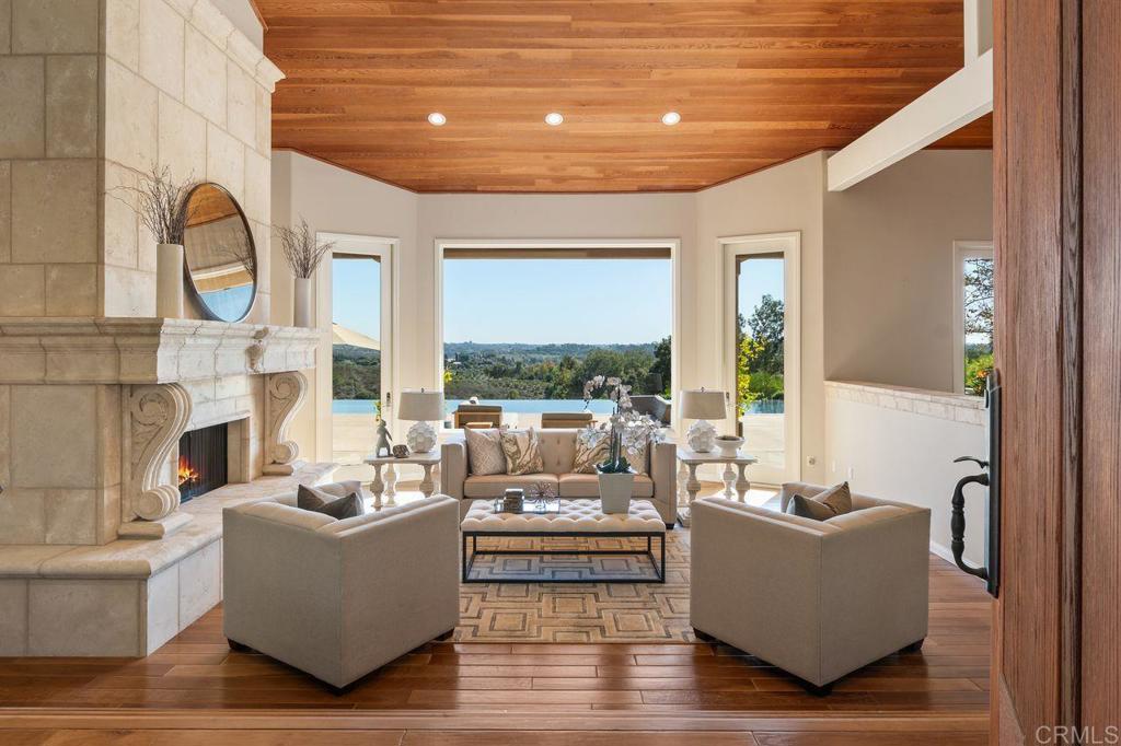 7196 Rancho La Cima Drive Rancho Santa Fe, CA 92067 - Photo 19 of 57 a living room with fireplace furniture and a large window
