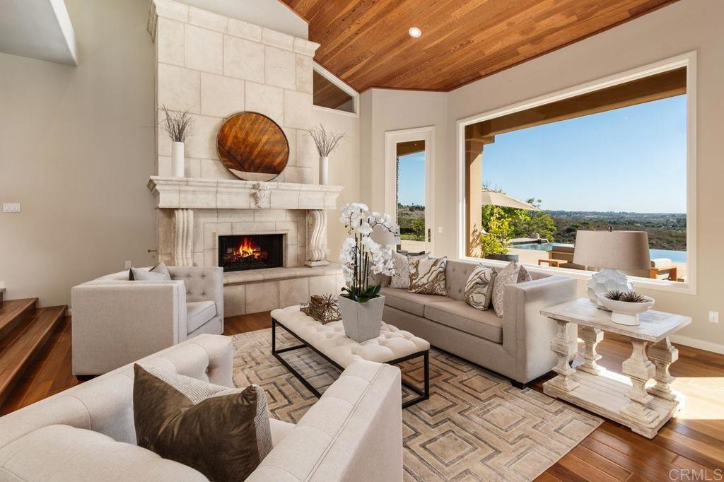 7196 Rancho La Cima Drive Rancho Santa Fe, CA 92067 - Photo 20 of 57 a living room with furniture a fireplace and a large window