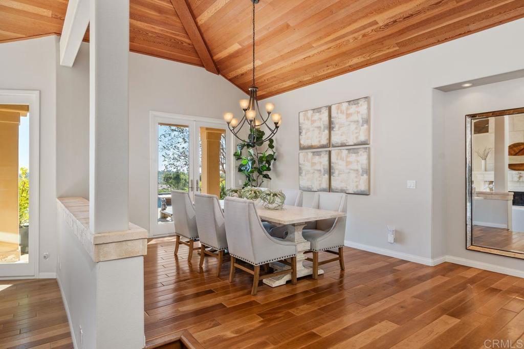 7196 Rancho La Cima Drive Rancho Santa Fe, CA 92067 - Photo 21 of 57 a dining room with wooden floor a chandelier a wooden table and chairs