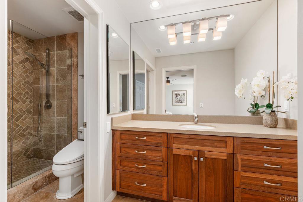7196 Rancho La Cima Drive Rancho Santa Fe, CA 92067 - Photo 40 of 57 a bathroom with a granite countertop sink a toilet a mirror and shower