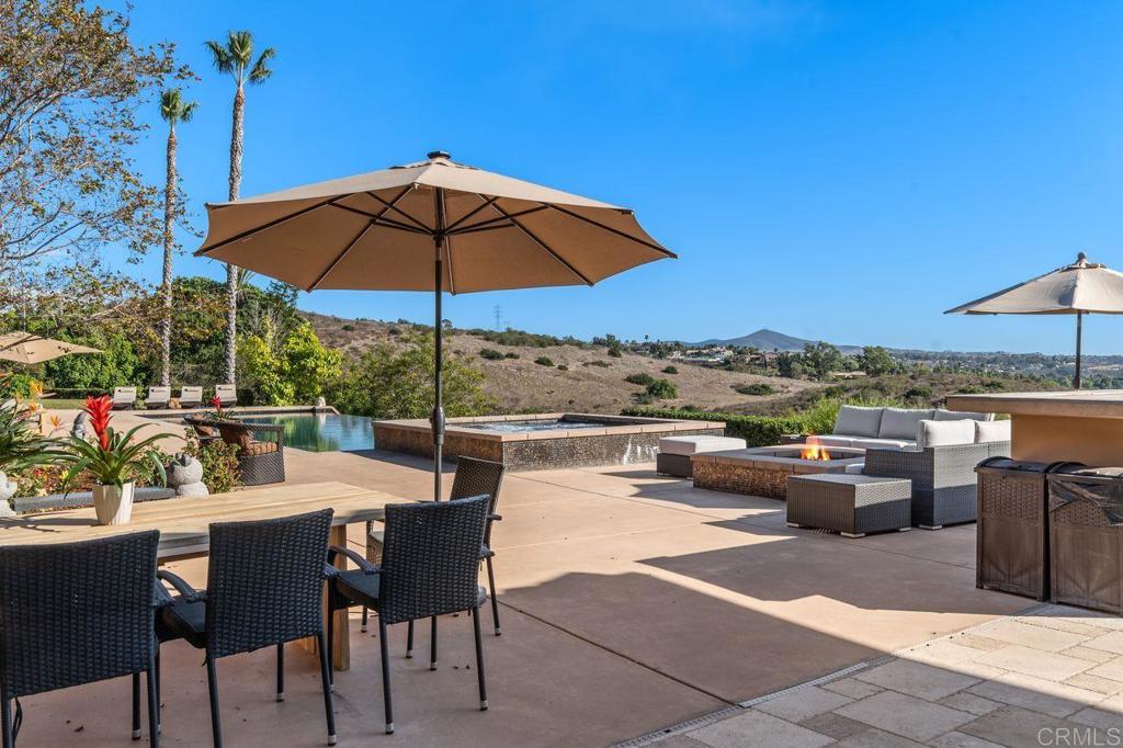 7196 Rancho La Cima Drive Rancho Santa Fe, CA 92067 - Photo 48 of 57 a view of a terrace with furniture and umbrella