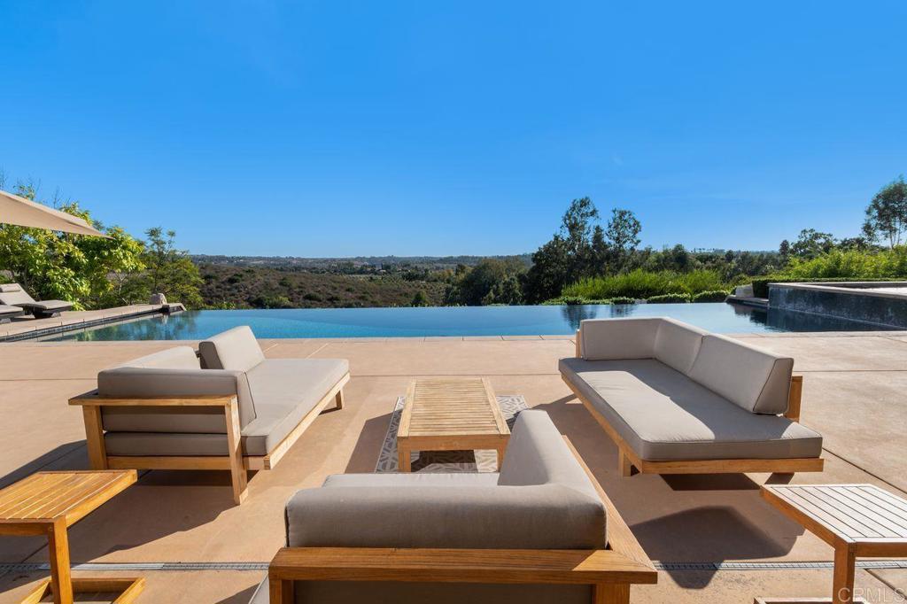 7196 Rancho La Cima Drive Rancho Santa Fe, CA 92067 - Photo 52 of 57 a view of a patio with couches table and chairs with wooden floor and fence