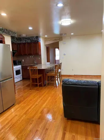 a living room with stainless steel appliances furniture a rug and a kitchen view