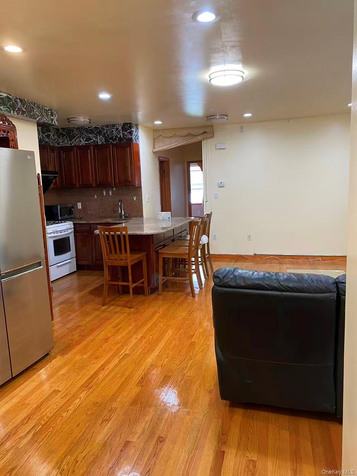 142-44 56th Road Queens, NY 11355 - Photo 1 of 1 a living room with stainless steel appliances furniture a rug and a kitchen view