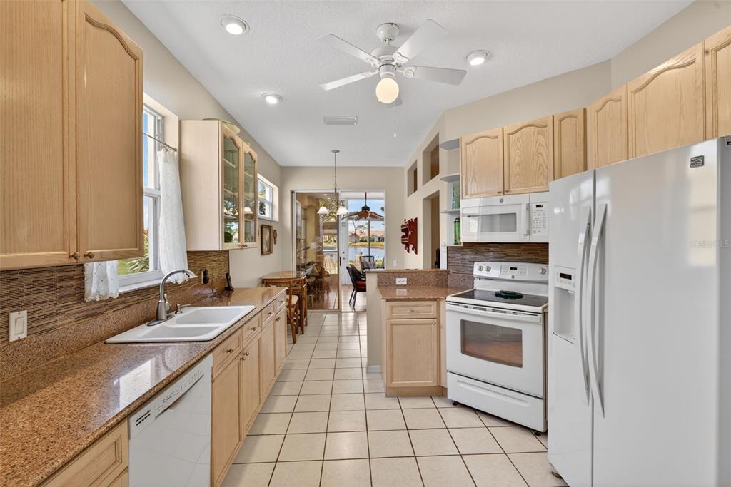4266 Summertree Road Venice, FL 34293 - Photo 15 of 64 a kitchen with stainless steel appliances a stove a sink a refrigerator white cabinets and couches with wooden floor