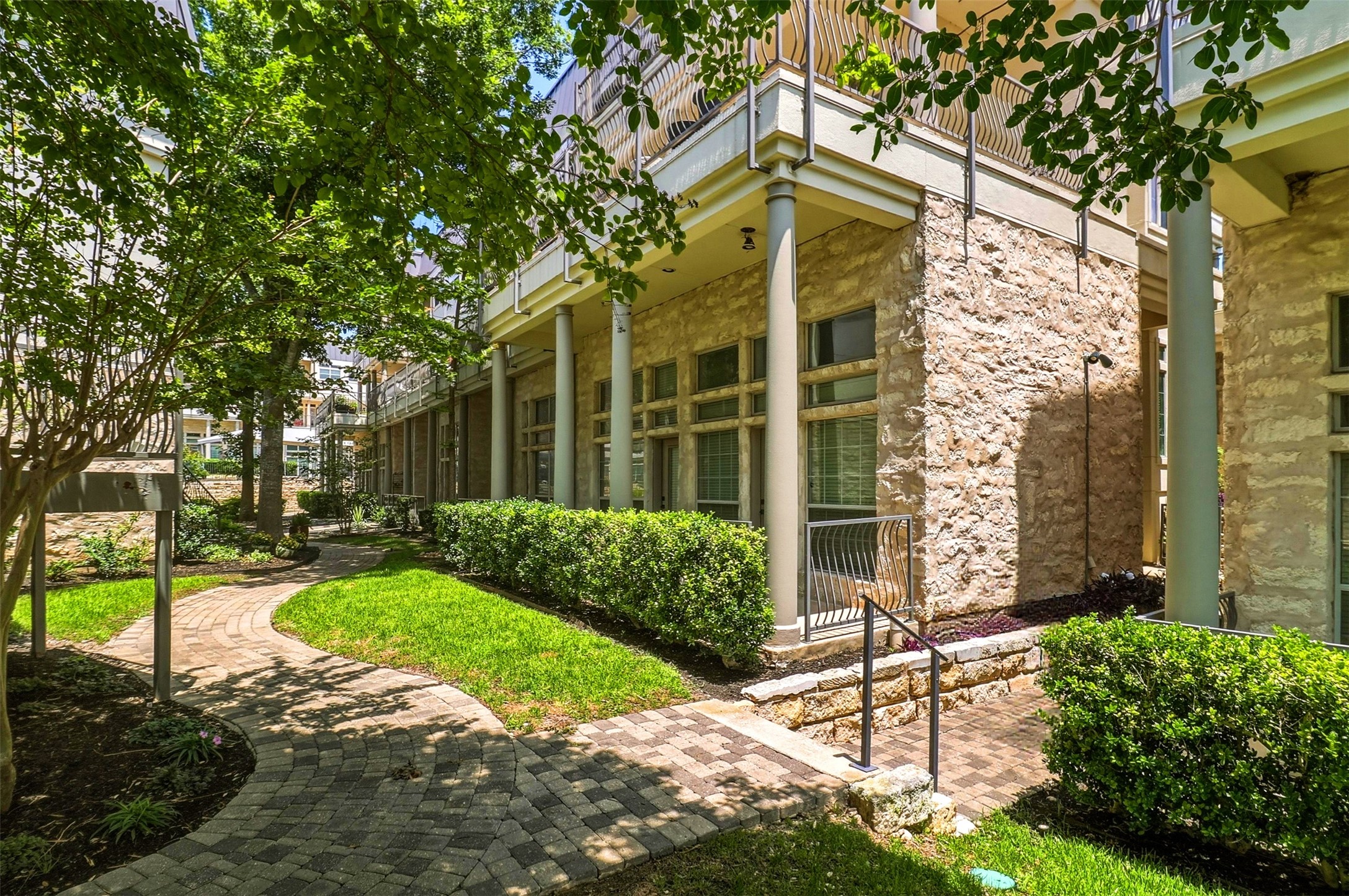 2918 Ranch Road 620, Unit 265 Austin, TX 78734 - Photo 24 of 40 A winding brick pathway meanders through verdant landscaping, leading to a charming stone-faced structure.