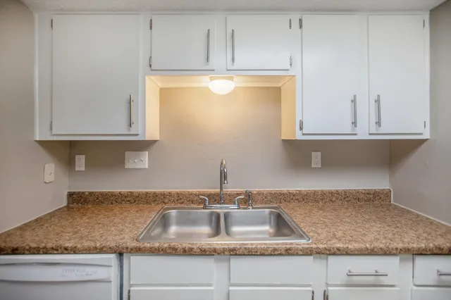 a kitchen with granite countertop white cabinets and a sink