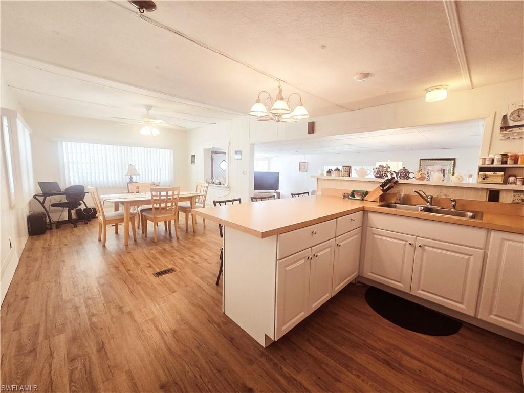 99 Moorhead Manor, Unit 99 Naples, FL 34112 - Photo 11 of 26 a kitchen with a sink a stove cabinets and wooden floor