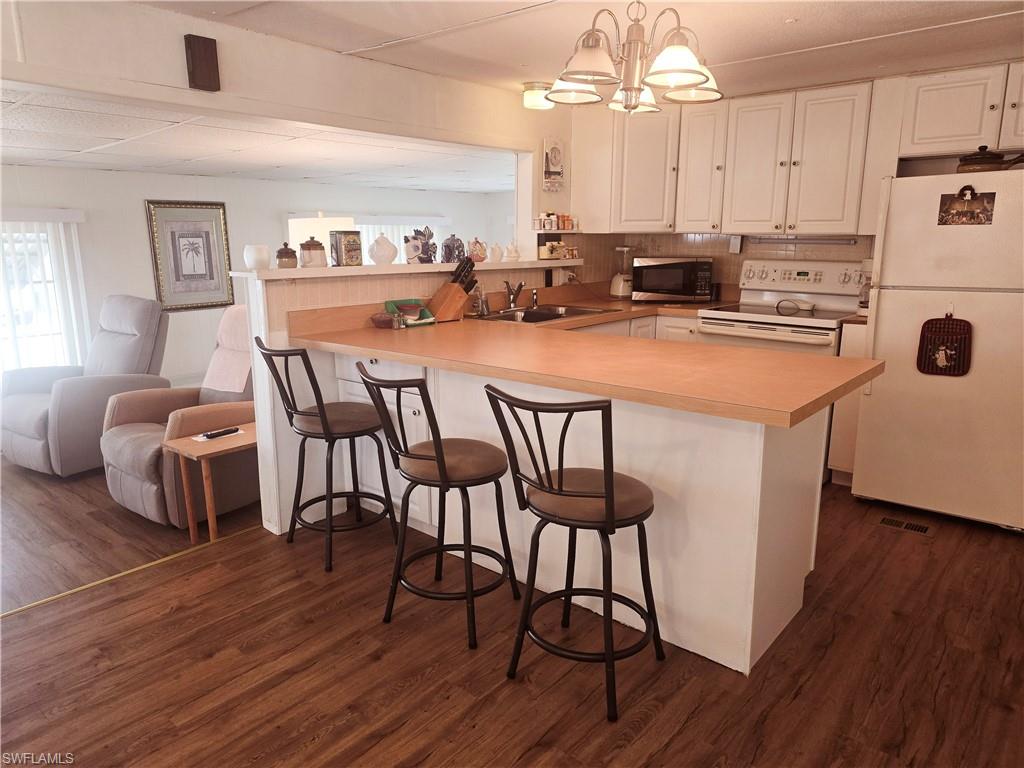 99 Moorhead Manor, Unit 99 Naples, FL 34112 - Photo 7 of 26 a kitchen with stainless steel appliances a dining table chairs a sink dishwasher and cabinets with wooden floor
