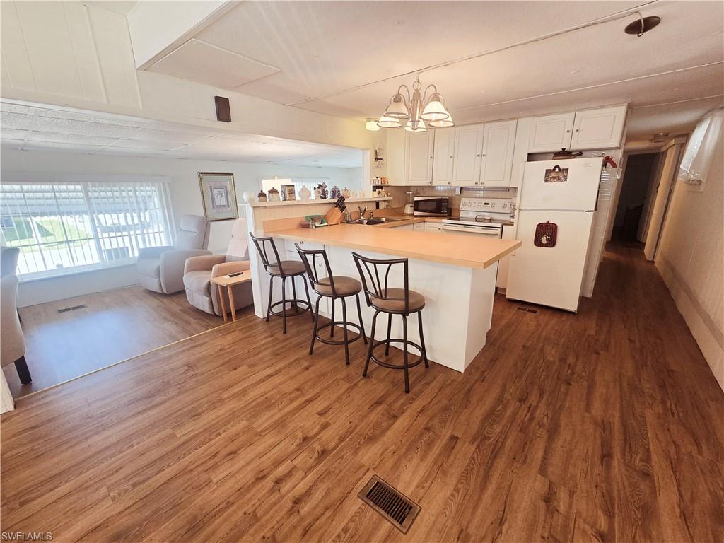 99 Moorhead Manor, Unit 99 Naples, FL 34112 - Photo 9 of 26 a kitchen with stainless steel appliances a dining table chairs a sink and dishwasher a refrigerator with wooden floor