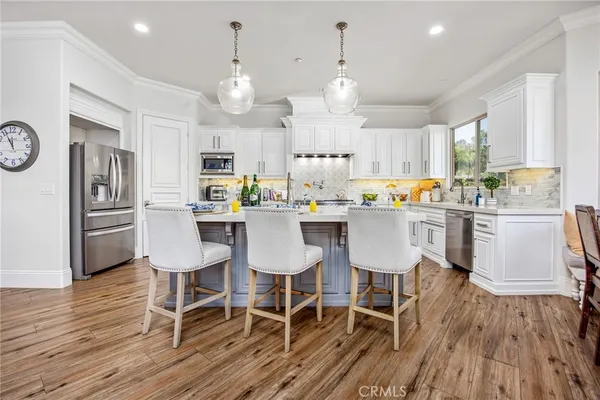 a kitchen with a dining table chairs wooden floor cabinets and stainless steel appliances