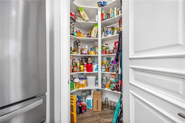 a large white kitchen with stainless steel appliances granite countertop a stove a sink a dining table and chairs with wooden floor