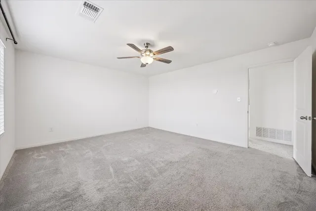 an empty room with chandelier fan and windows