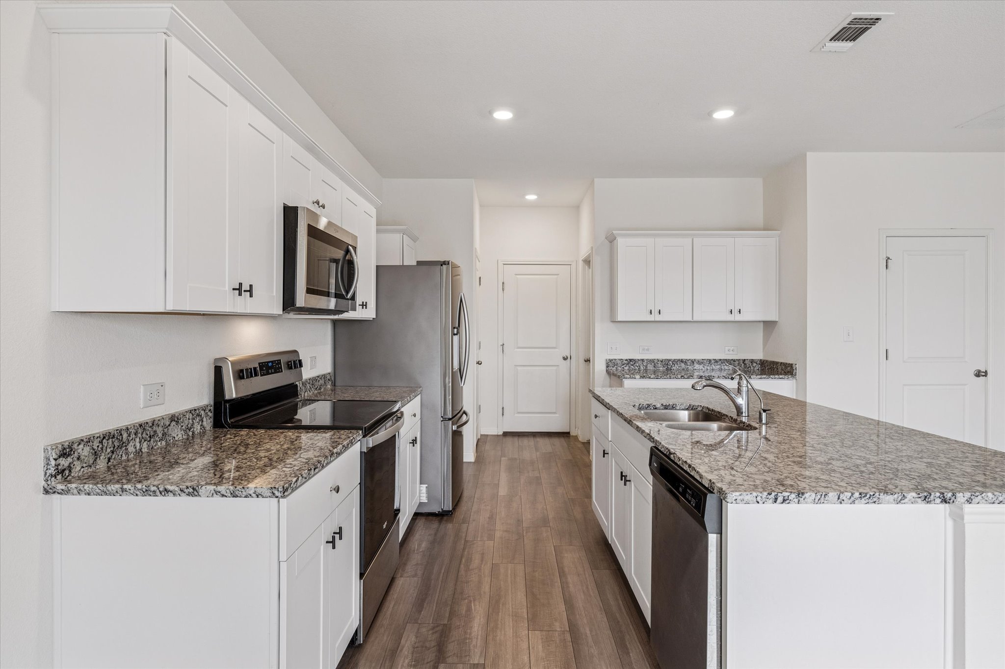208 Night Riders Way Jarrell, TX 76537 - Photo 3 of 31 a kitchen with stainless steel appliances granite countertop a stove top oven a sink a refrigerator and white cabinets with wooden floor