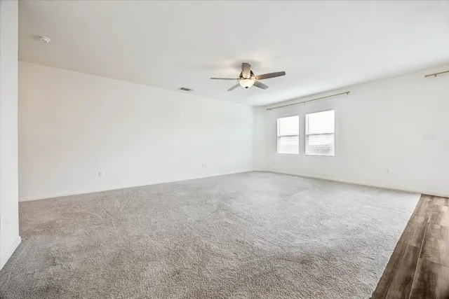 an empty room with windows and ceiling fan