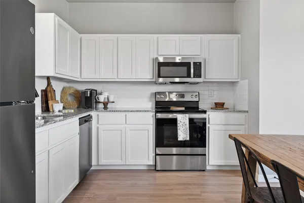 a kitchen with stainless steel appliances granite countertop a stove a sink dishwasher a microwave oven with cabinets and wooden floor