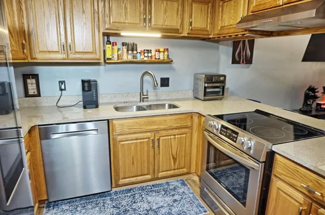 a kitchen with stainless steel appliances granite countertop a sink a stove a refrigerator and cabinets