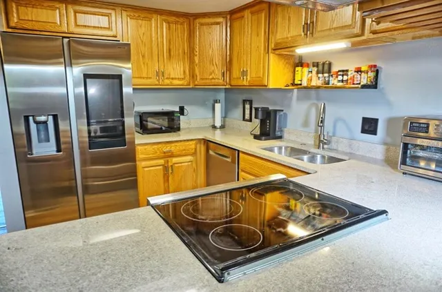 a kitchen with stainless steel appliances granite countertop a sink and a refrigerator