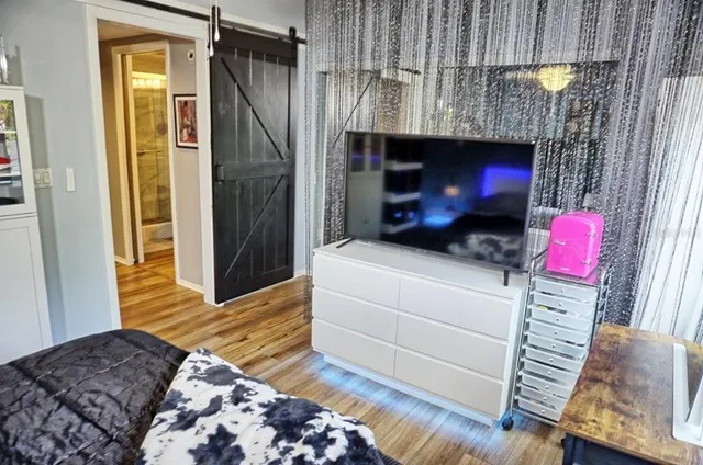 a bedroom with a bed a flat screen tv and dresser