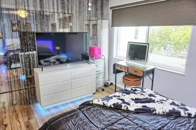 a bedroom with a bed a flat screen tv and guitar
