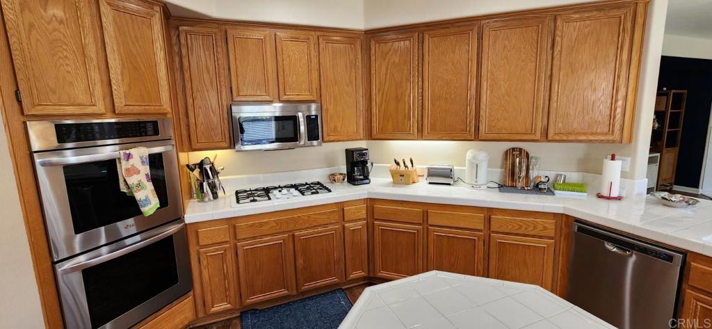 6848 Moorhen Place Carlsbad, CA 92009 - Photo 15 of 53 a kitchen with stainless steel appliances granite countertop a refrigerator sink and cabinets