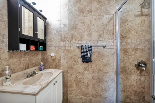 a bedroom with a bed a couch and a flat tv screen on the dresser