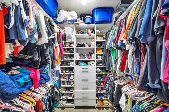 a view of walk in closet with clothes and shoes