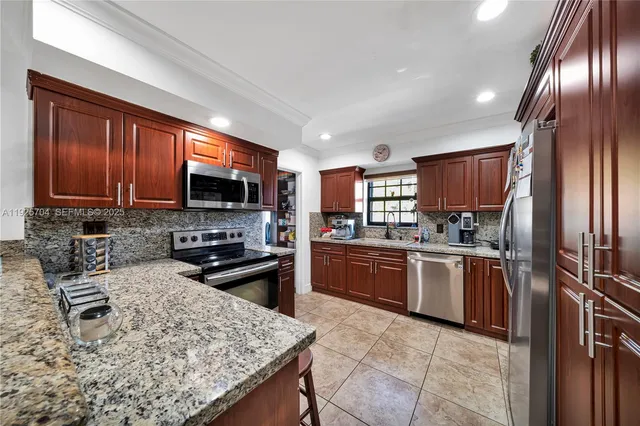 a kitchen with stainless steel appliances granite countertop a sink window and cabinets