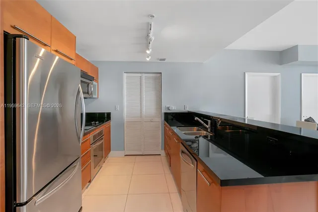 a kitchen with stainless steel appliances granite countertop a refrigerator a sink and a stove
