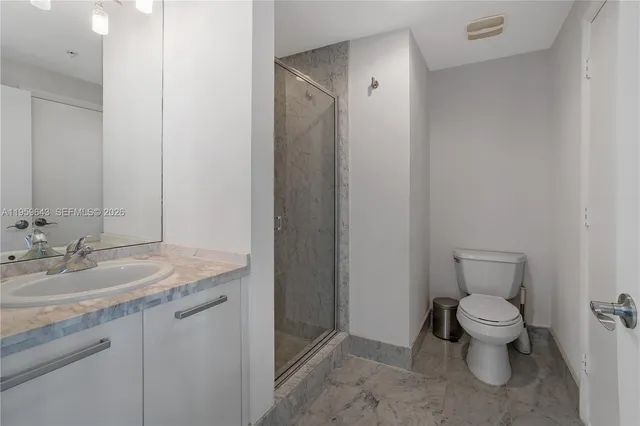 a bathroom with a granite countertop toilet a sink and a mirror