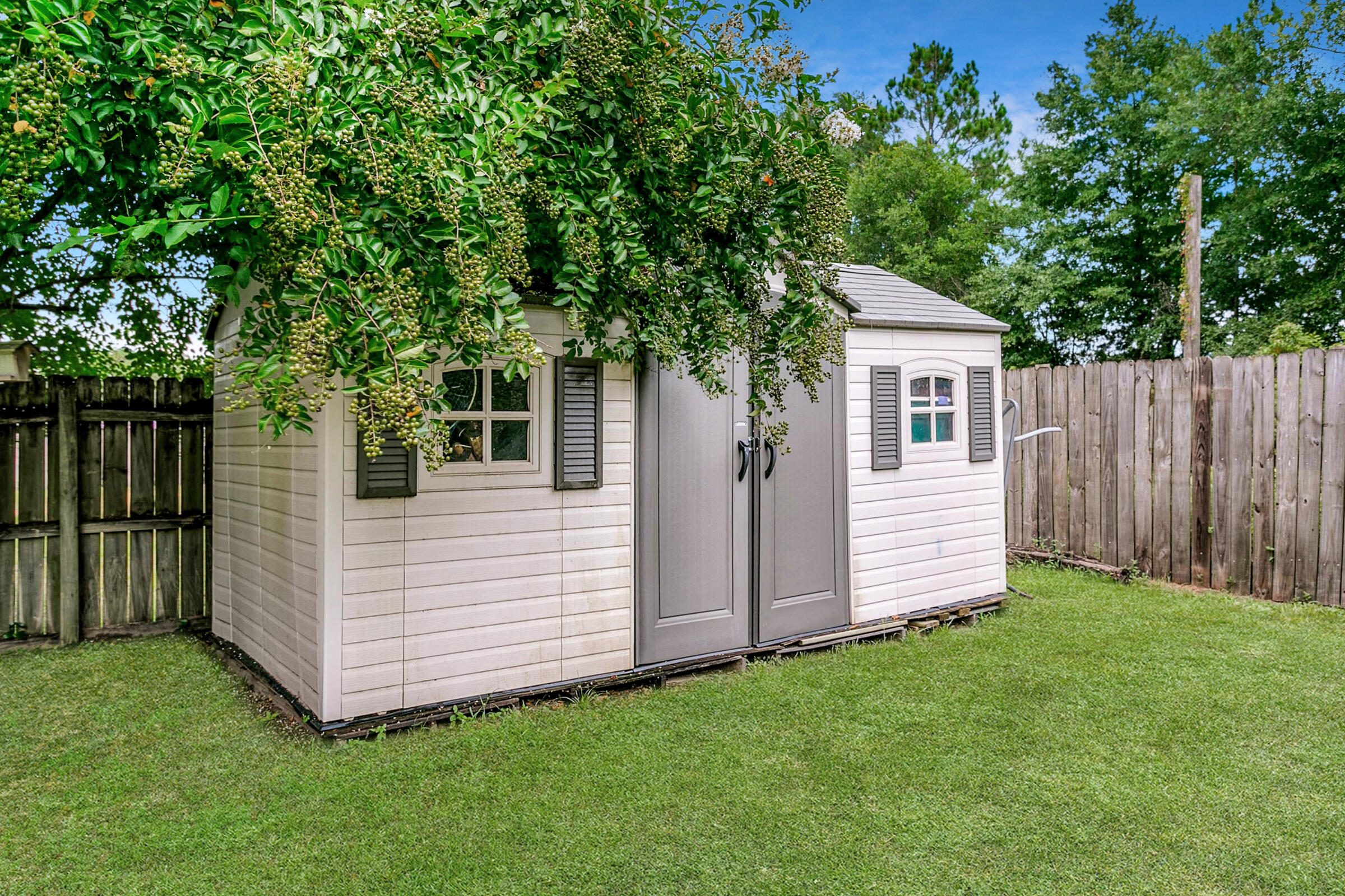 2246 Titanium Drive Crestview, FL 32536 - Photo 24 of 38 a view of a white house with a small yard and a large tree