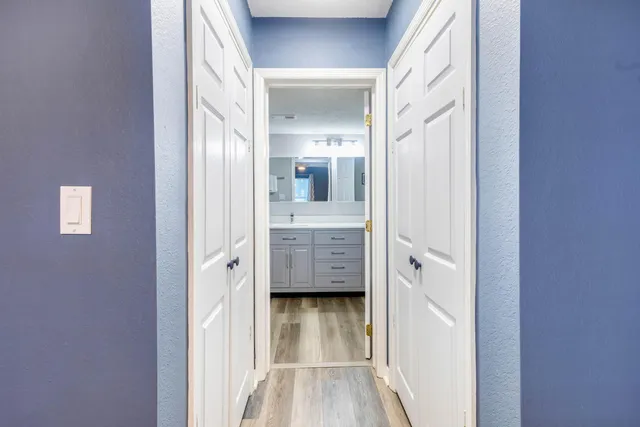 a view of a hallway with wooden floor and a bathroom