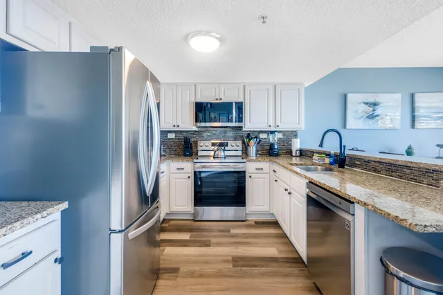 a kitchen with granite countertop a refrigerator stove and sink
