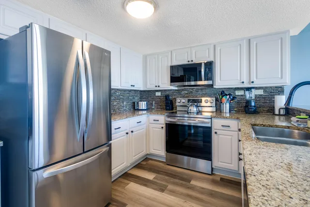 a kitchen with stainless steel appliances granite countertop a refrigerator stove a sink and a granite counter tops