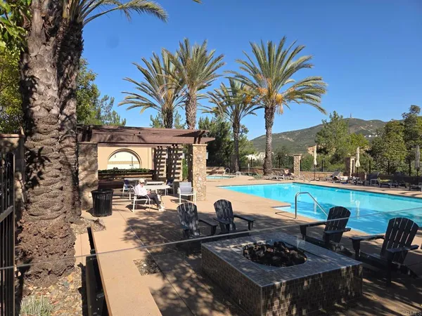 a view of a swimming pool with lawn chairs under an umbrella