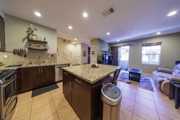 a kitchen with a stove a sink a kitchen island and chairs in it