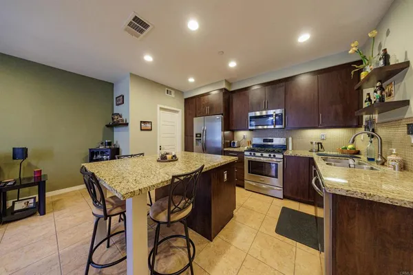 a kitchen with kitchen island granite countertop wooden cabinets and refrigerator