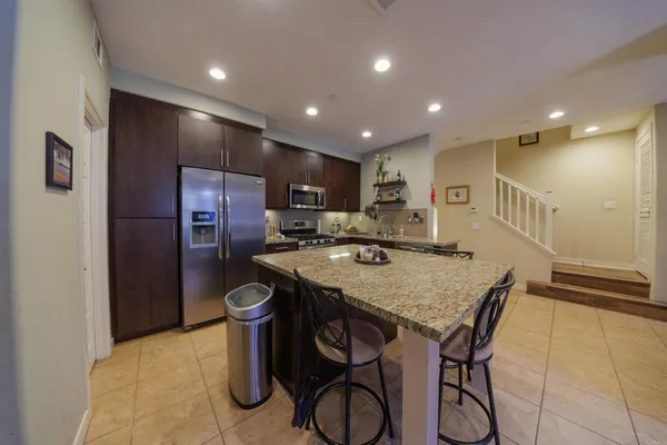 a kitchen with stainless steel appliances granite countertop a refrigerator and a stove top oven with wooden floor