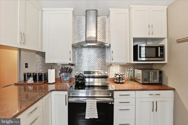 a kitchen with stainless steel appliances granite countertop a stove and white cabinets