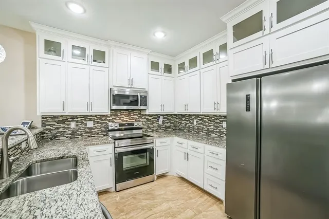 a kitchen with stainless steel appliances granite countertop a stove a sink and a refrigerator