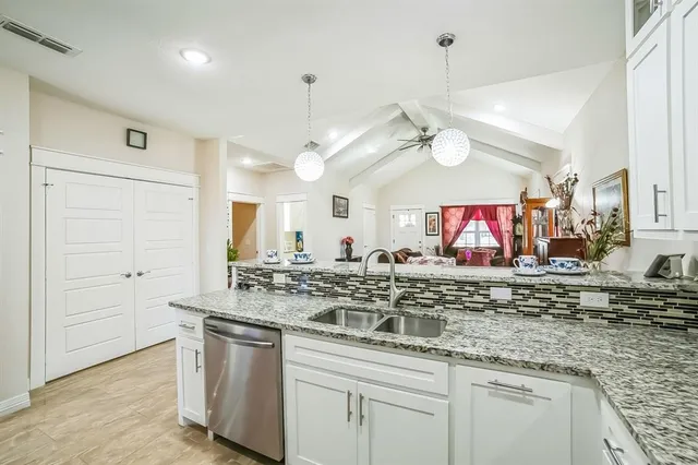 a kitchen with stainless steel appliances granite countertop a sink and a white cabinets