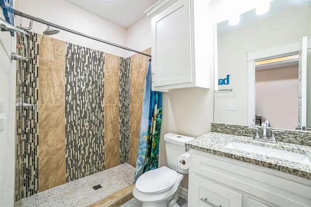 a bathroom with a granite countertop sink toilet and shower