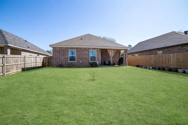 a view of a house with a yard and a large tree
