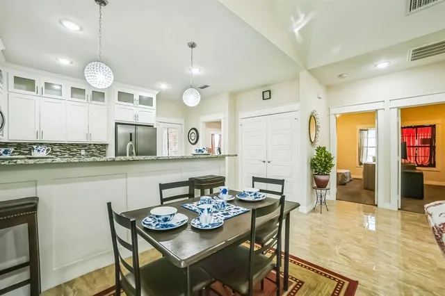 a open dining room with stainless steel appliances kitchen island granite countertop a table chairs and a refrigerator