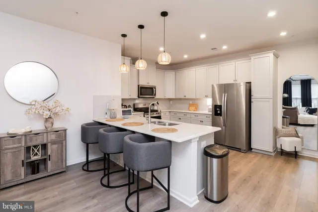 a kitchen with stainless steel appliances granite countertop a sink a stove a refrigerator and island with wooden floor