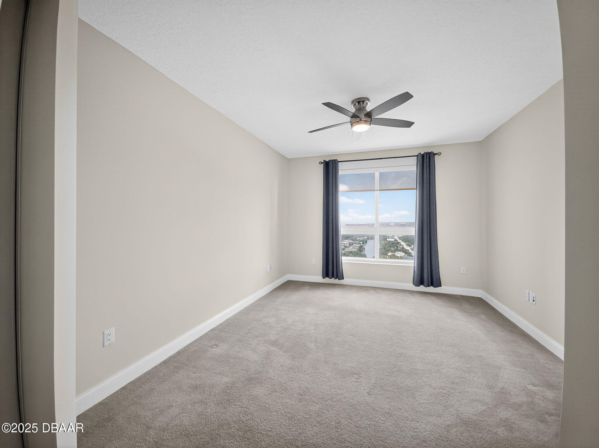 231 Riverside Drive, Unit 2409 Holly Hill, FL 32117 - Photo 22 of 24 an empty room with windows and chandelier fan