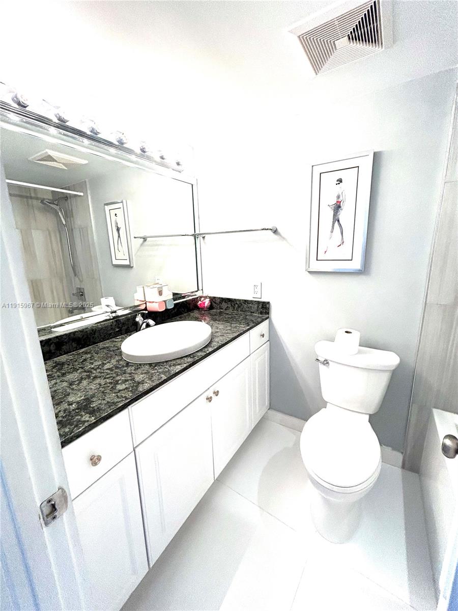 200 Diplomat Parkway, Unit 721 Hallandale Beach, FL 33009 - Photo 14 of 47 a bathroom with a granite countertop sink mirror a toilet and a bathtub